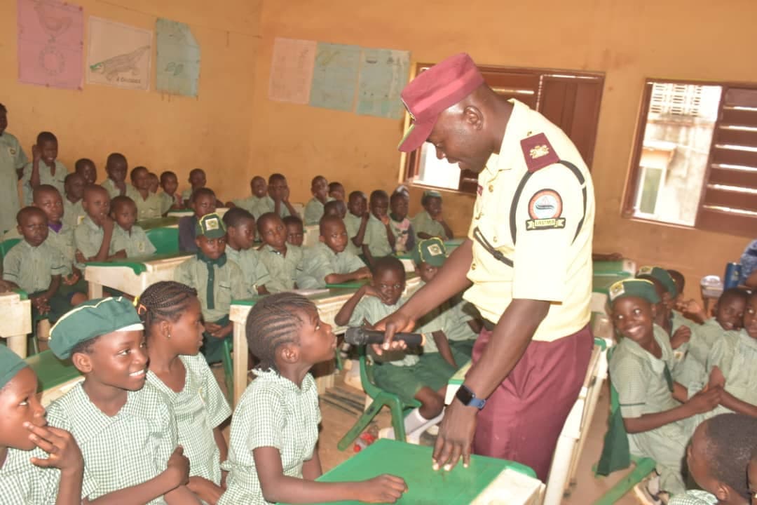 A LASTMA officer talks with primary pupils at their desks during a road safety lesson