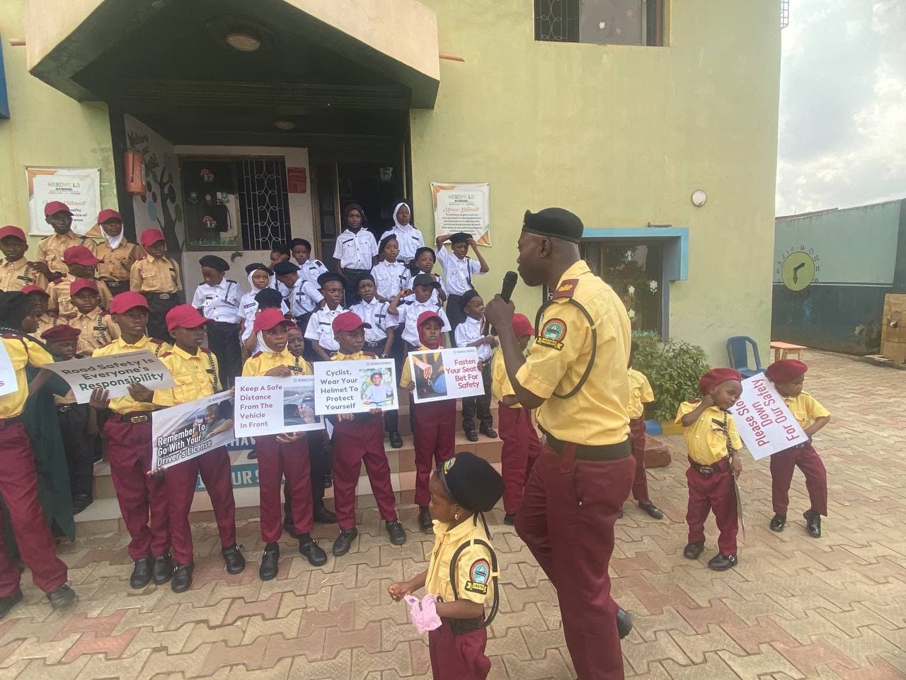 Pupils in Traffic Safety Advocacy Club uniform line up with road safety placards