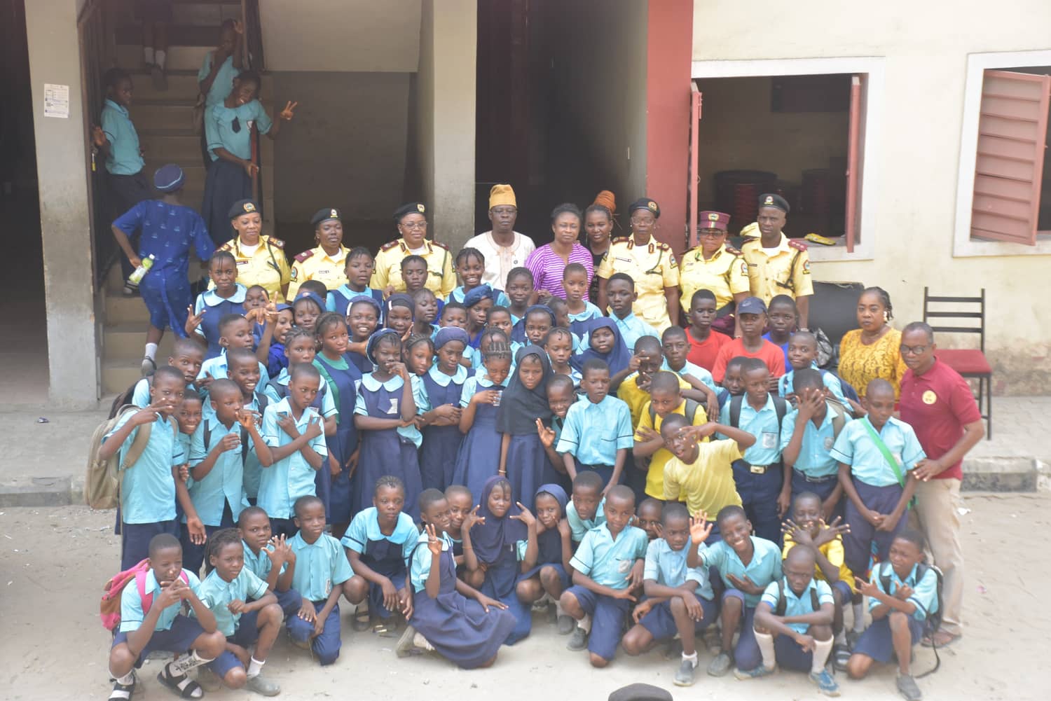 A full school of pupils in blue uniform crowds together for a photograph with LASTMA officers after a road safety visit
