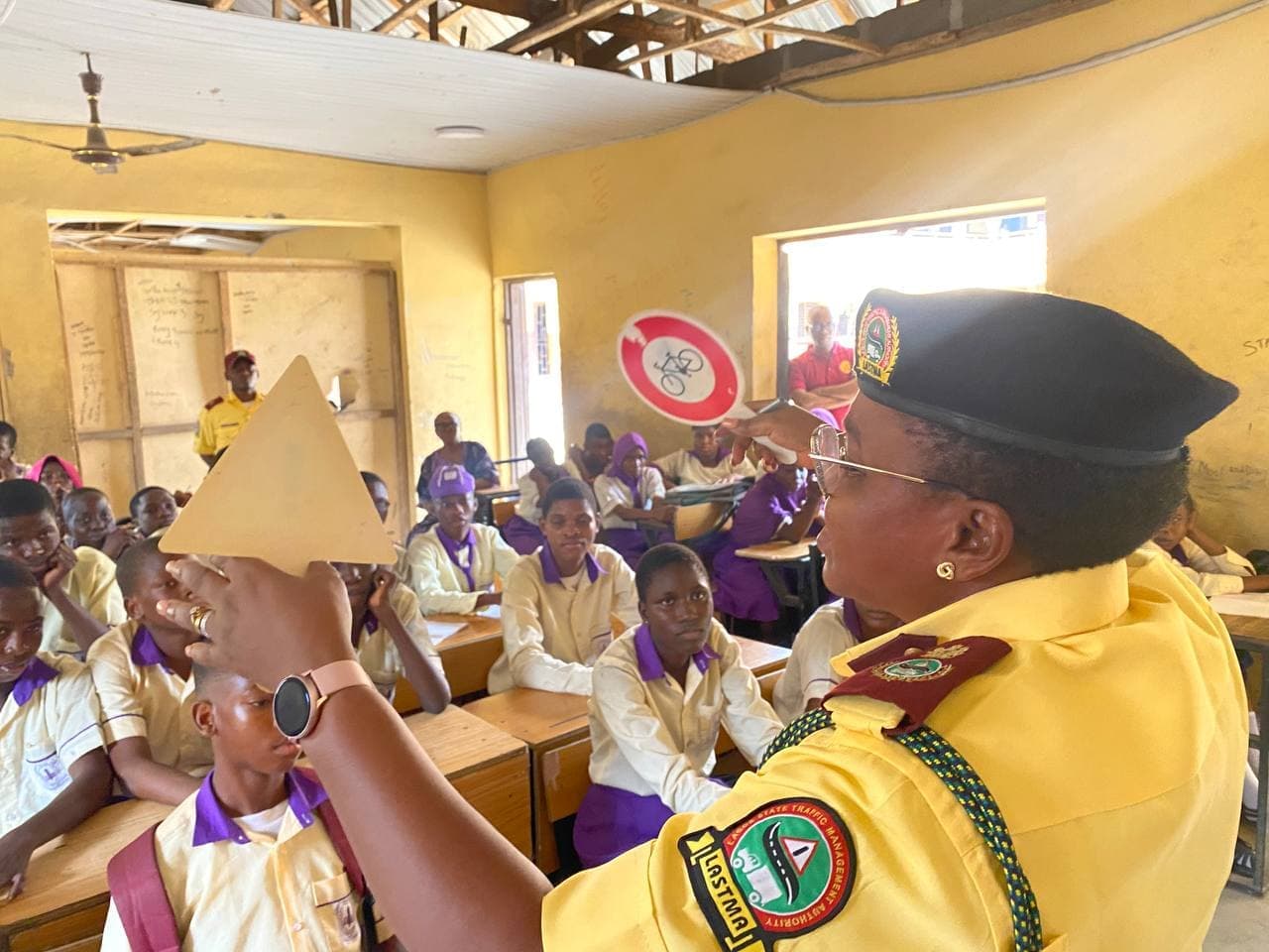 A LASTMA officer holds up a triangular road sign for secondary pupils to identify
